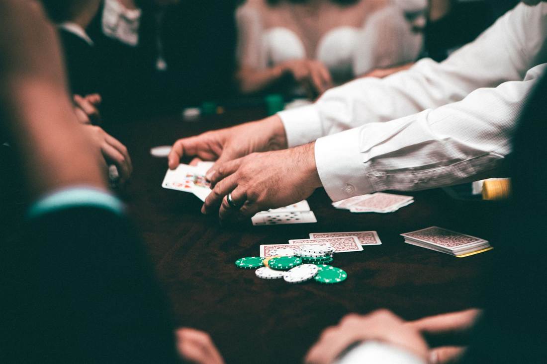 Dealer membagikan kartu di meja poker dengan tumpukan chip
